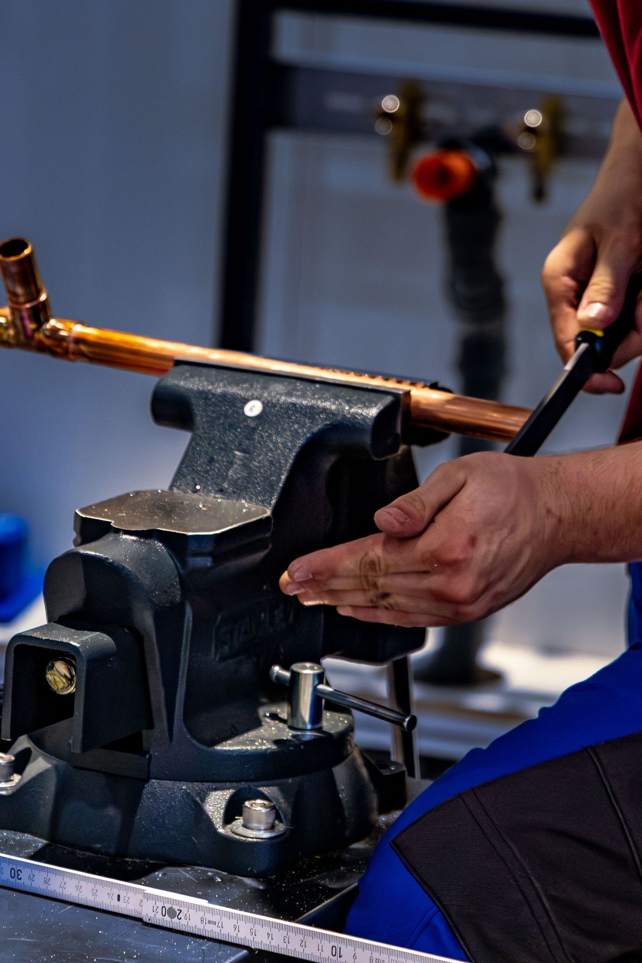 Craftsman working copper pipe with precision tools