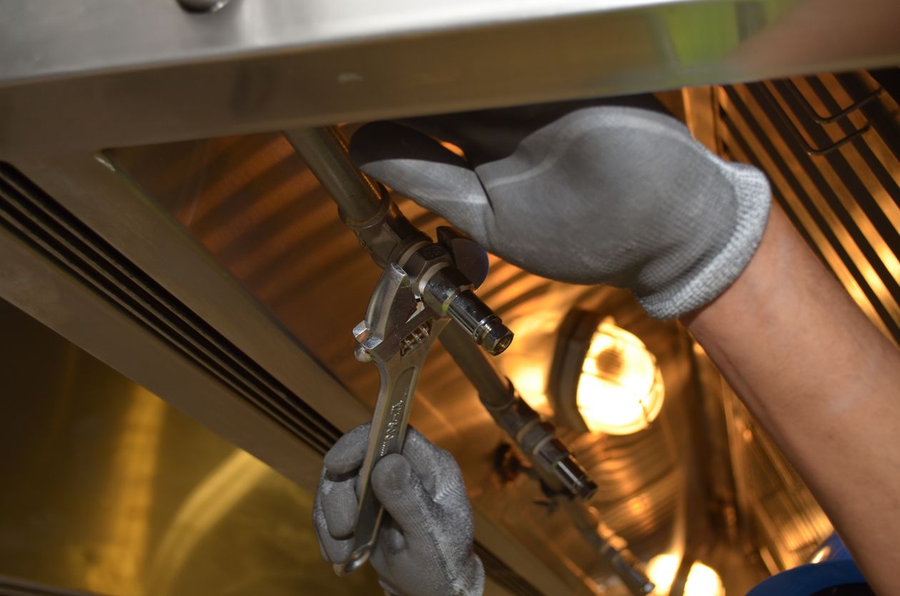 Tri-Tek plumber tightening a pipe fitting with a wrench